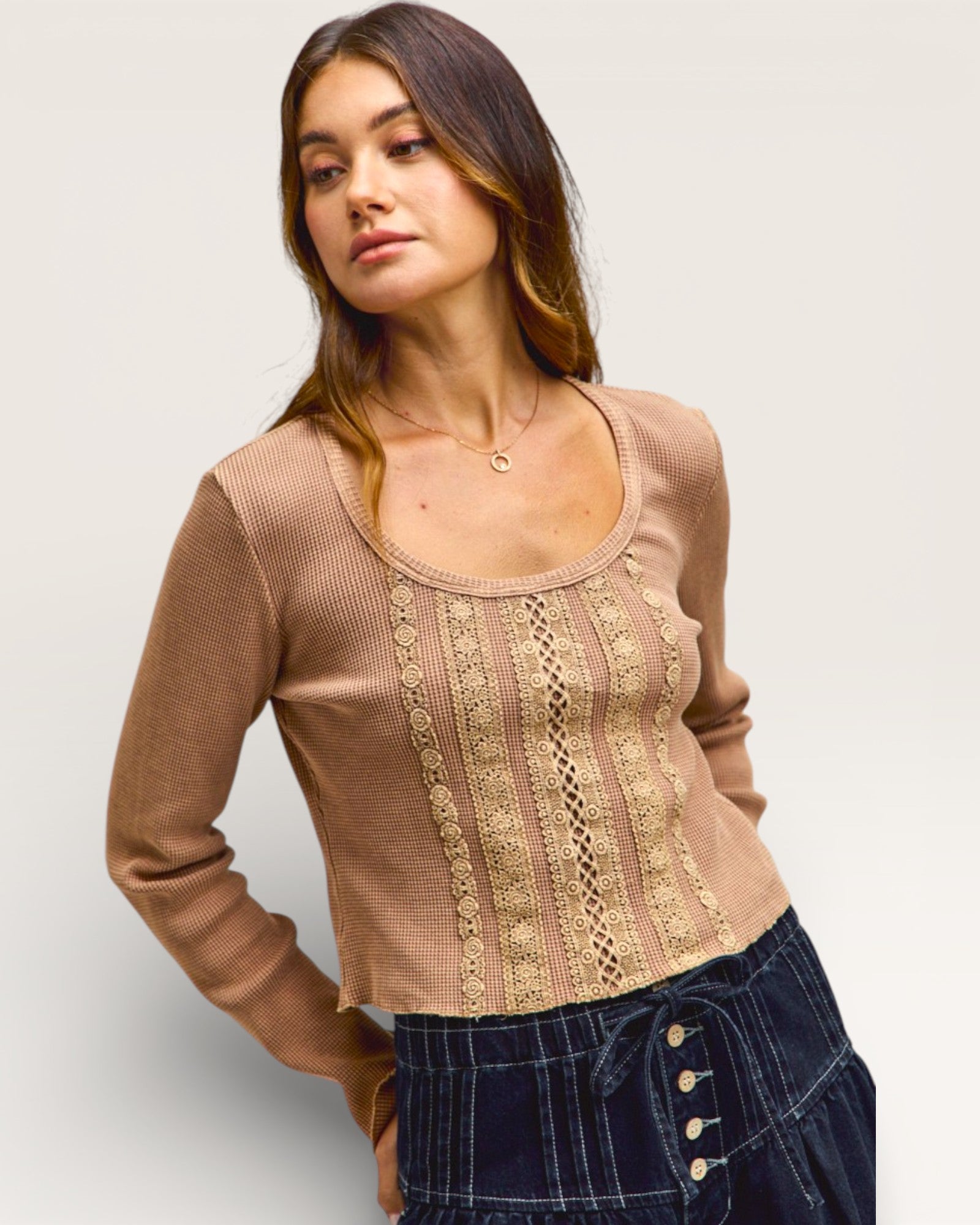 Woman wearing a brown lace top with a plain background