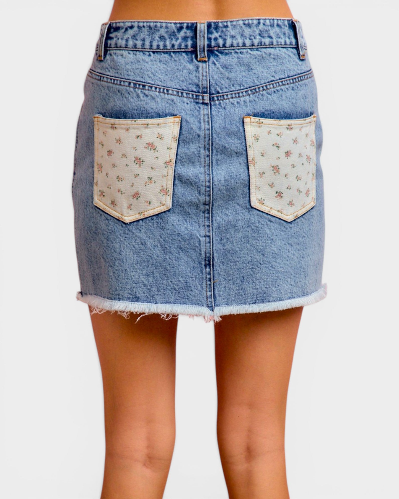 Denim skirt with floral pocket designs on a white background