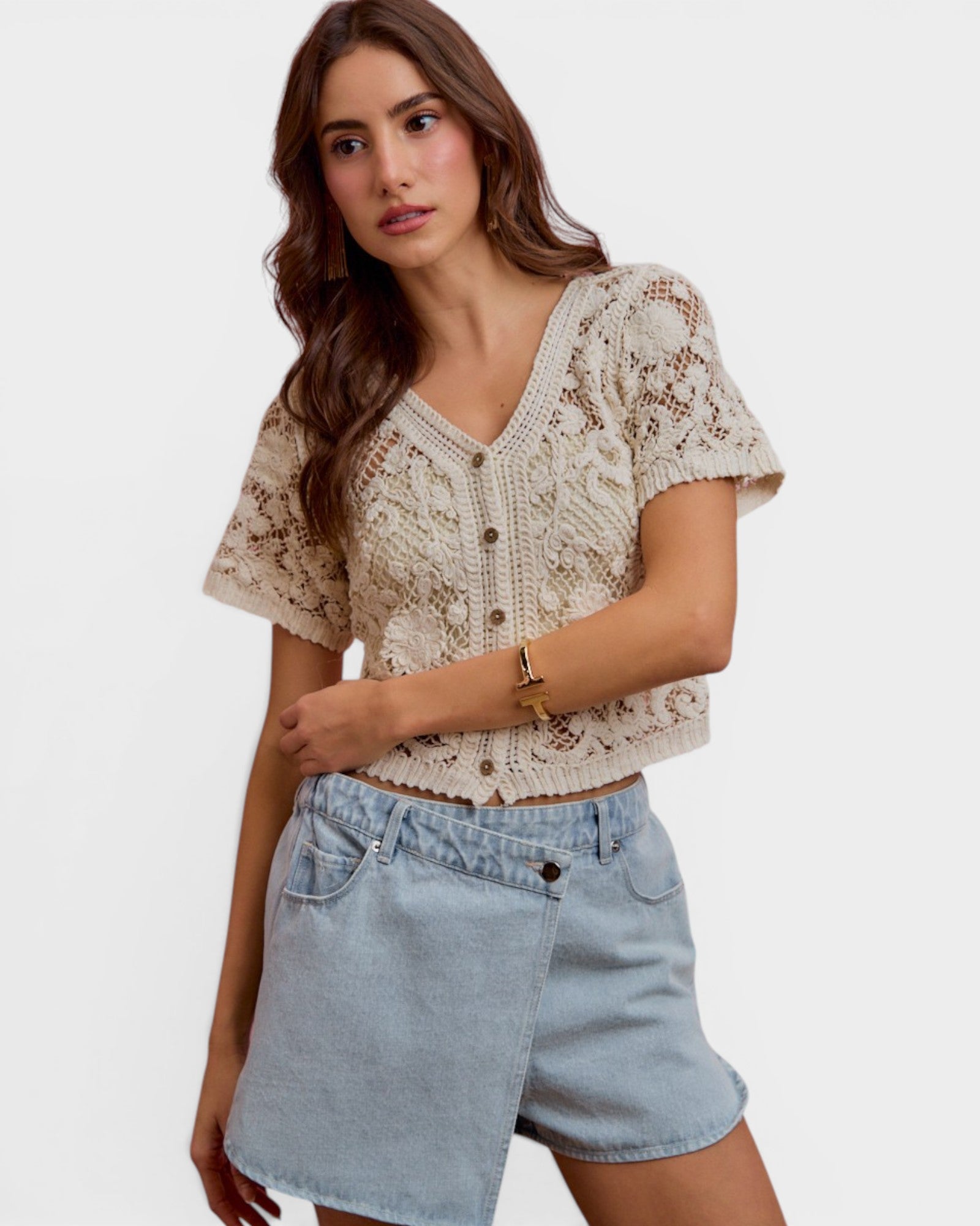Woman wearing a lace top and denim shorts on a white background