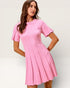 Woman wearing a pink dress with short sleeves on a light background