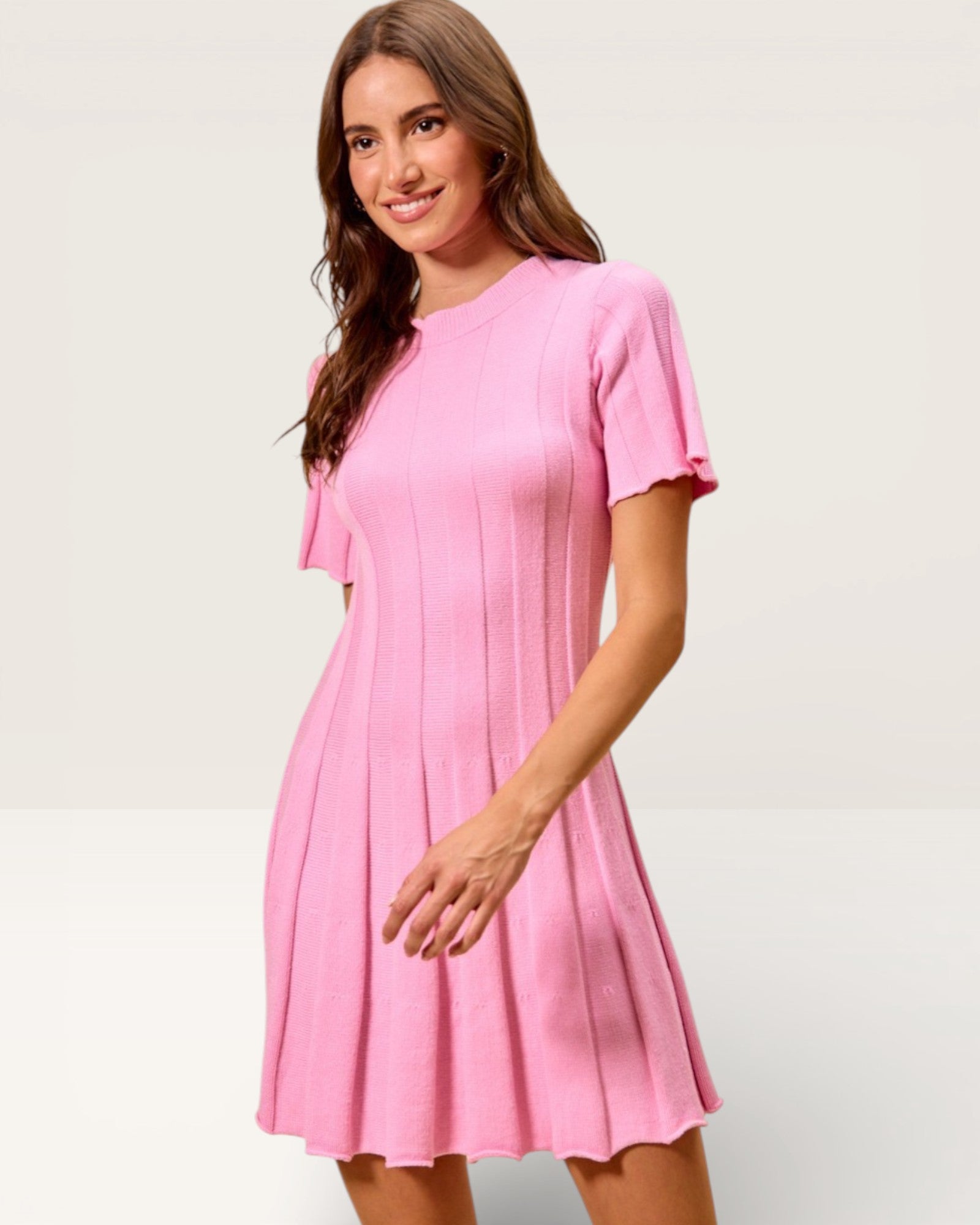 Woman wearing a pink dress against a plain background