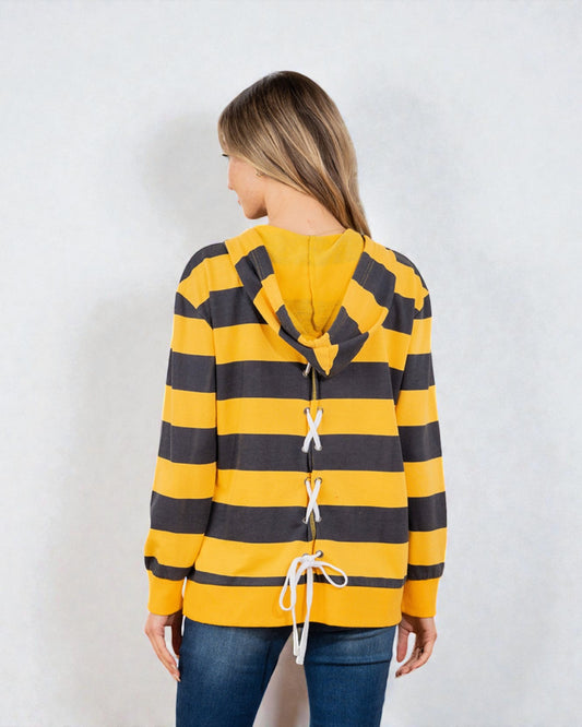 Person wearing a yellow and black striped hoodie with lace-up details on a white background