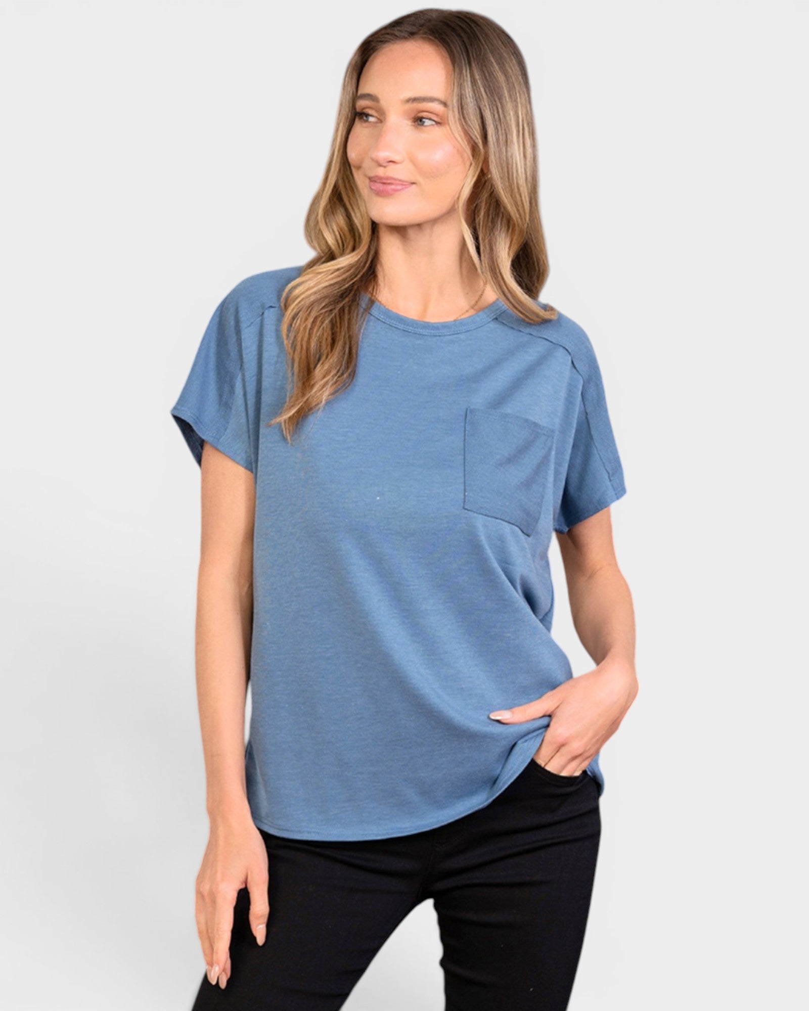Woman wearing a blue t-shirt with a pocket on a plain background