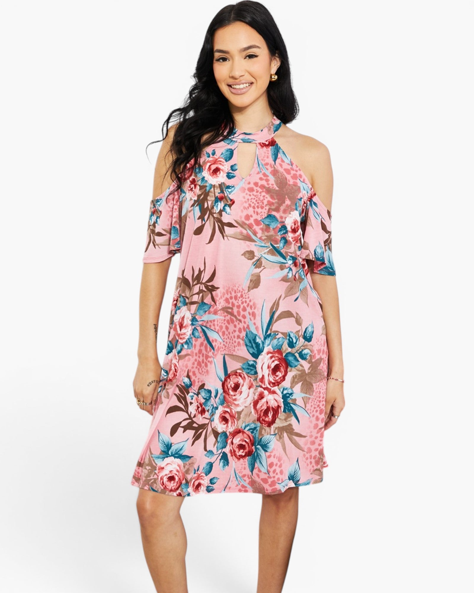 A woman modeling a pink cold-shoulder midi dress with a vibrant floral print in shades of red, blue, and brown, set against a plain white studio background.