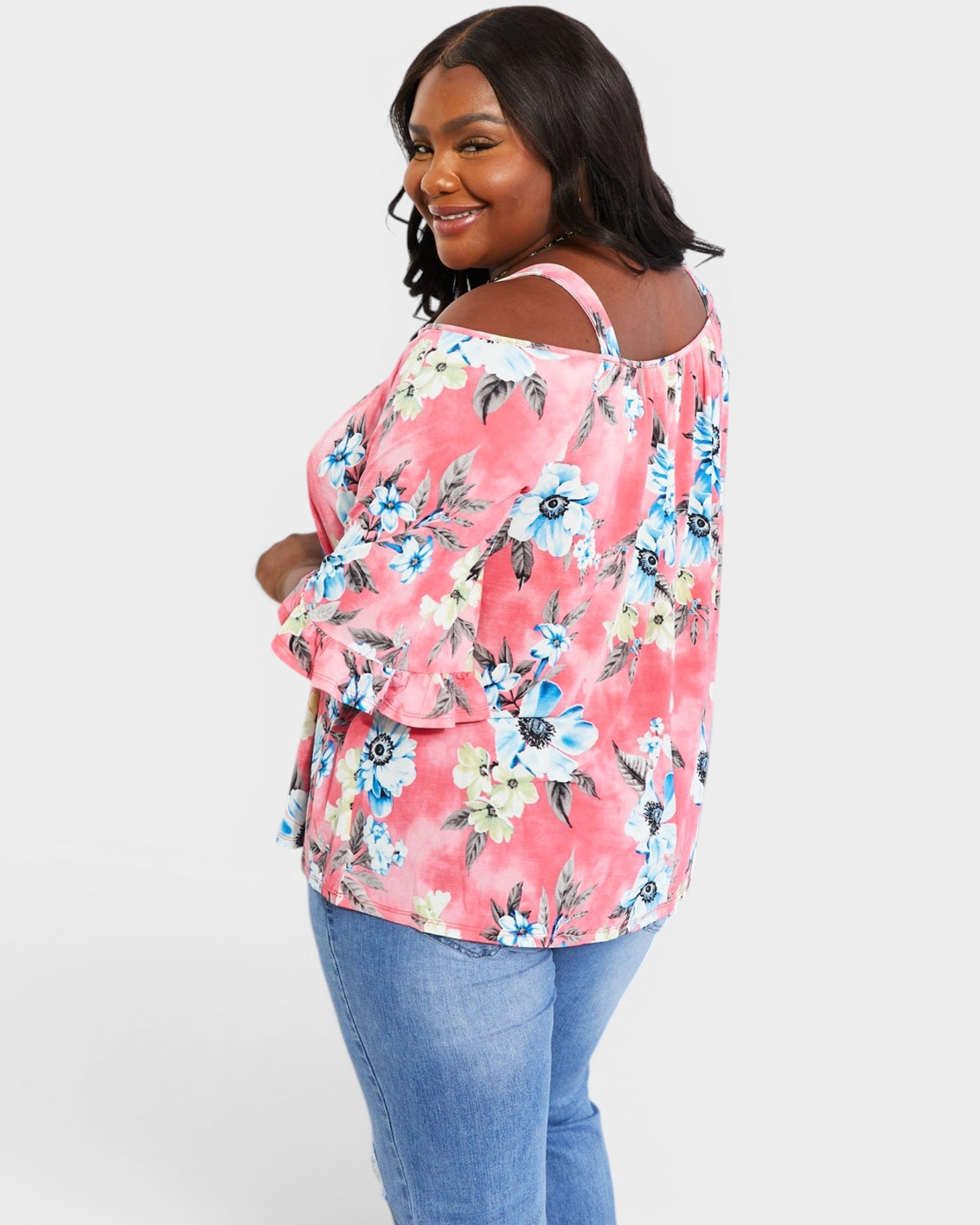 Woman wearing a pink floral blouse and blue jeans on a white background