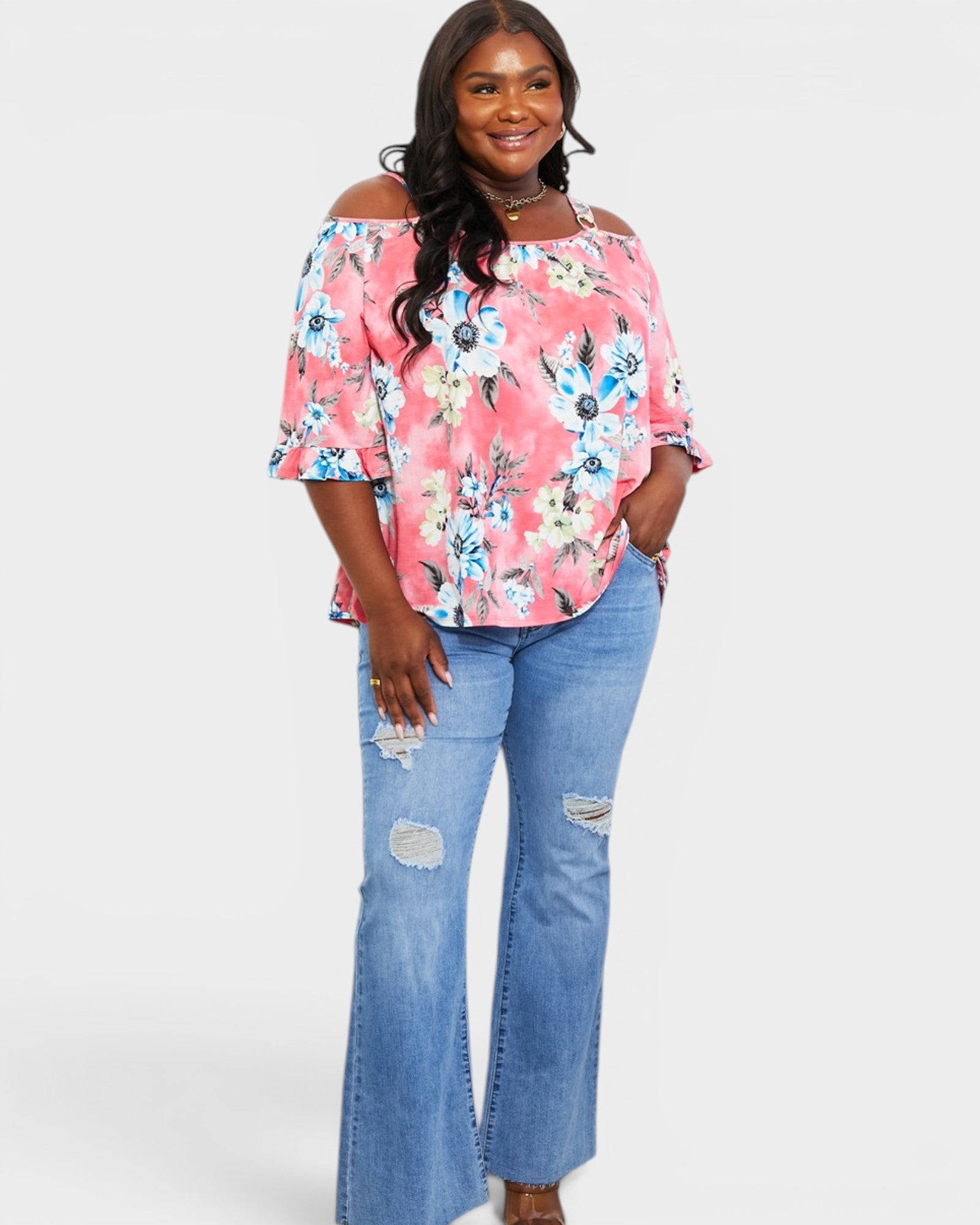 Woman wearing a floral off-shoulder top and blue jeans on a white background