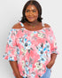 Woman wearing a pink floral off-shoulder top against a white background