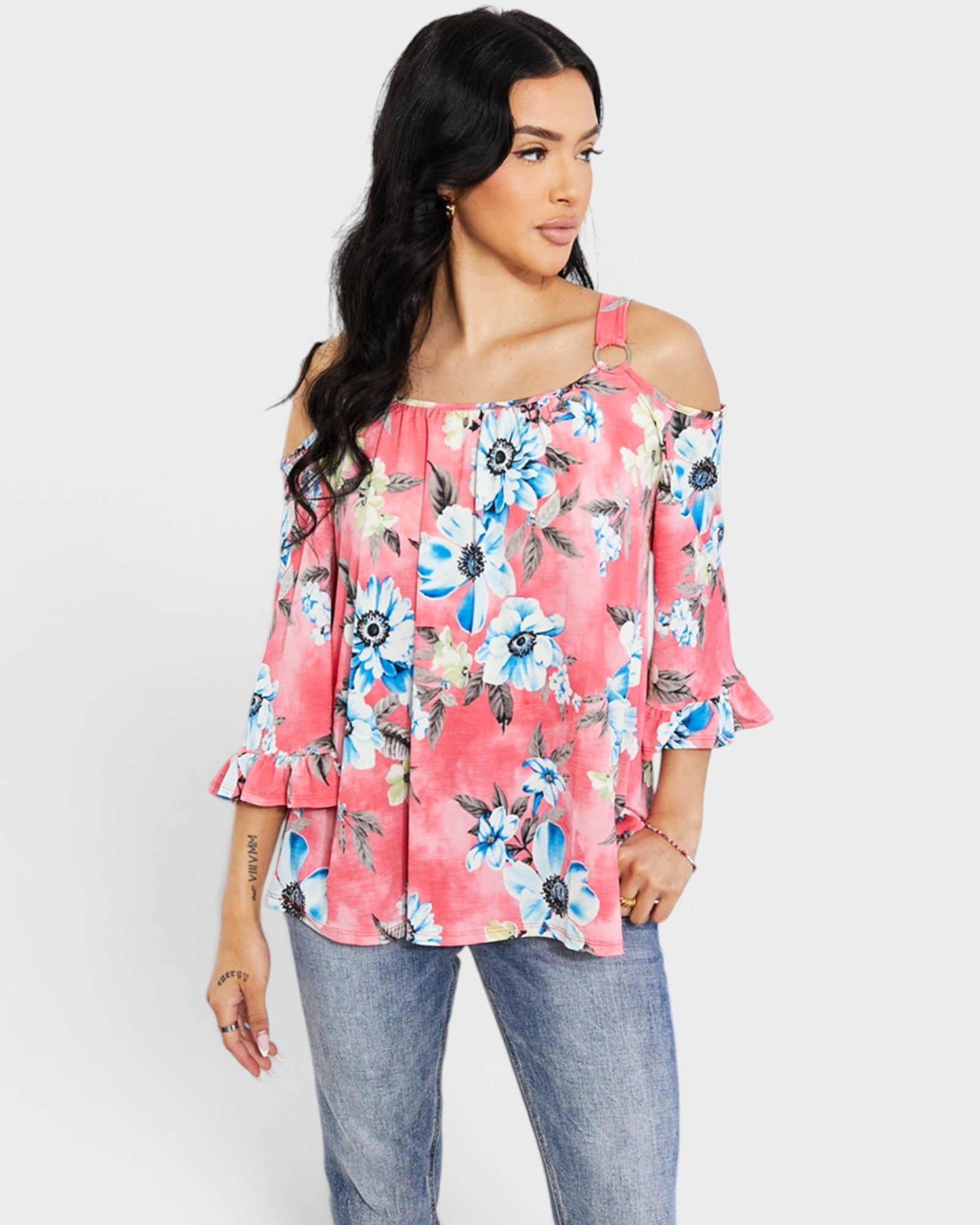 Woman wearing a floral off-shoulder top and jeans on a white background