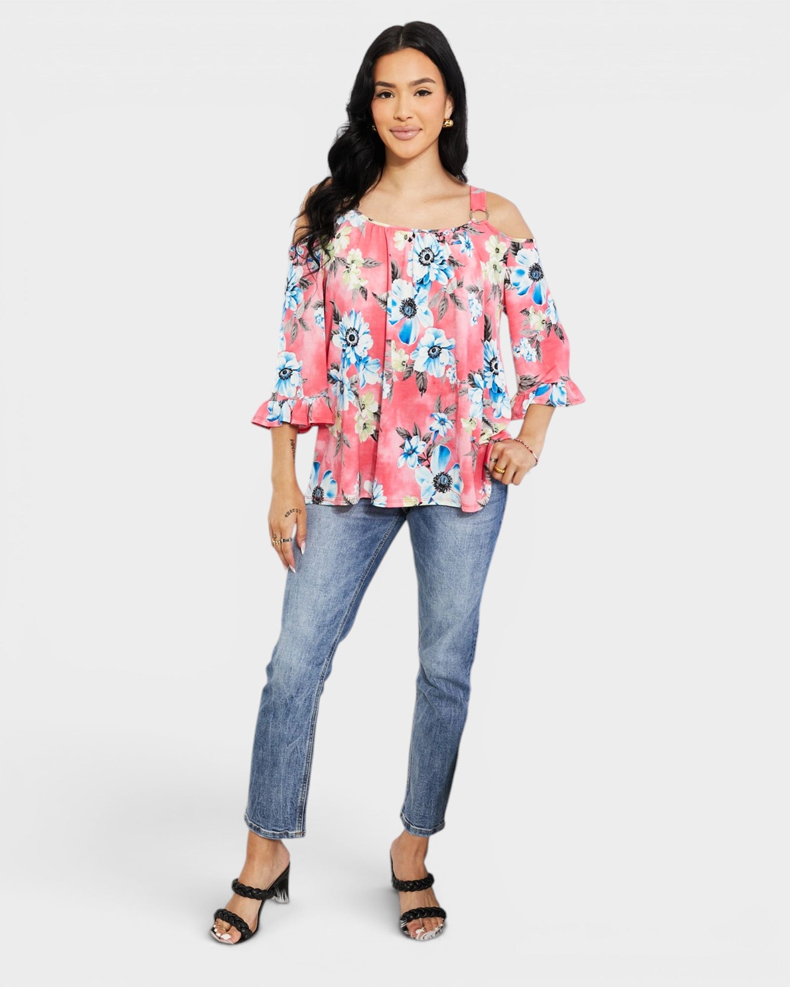 Woman wearing a floral off-shoulder top and jeans on a white background