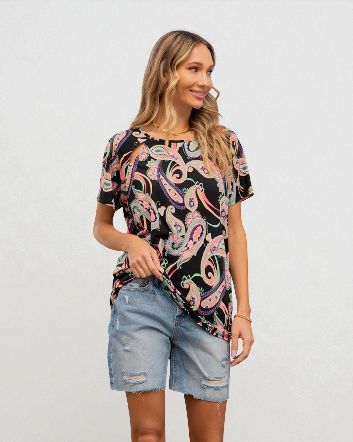 Woman wearing a colorful paisley shirt and denim shorts on a white background
