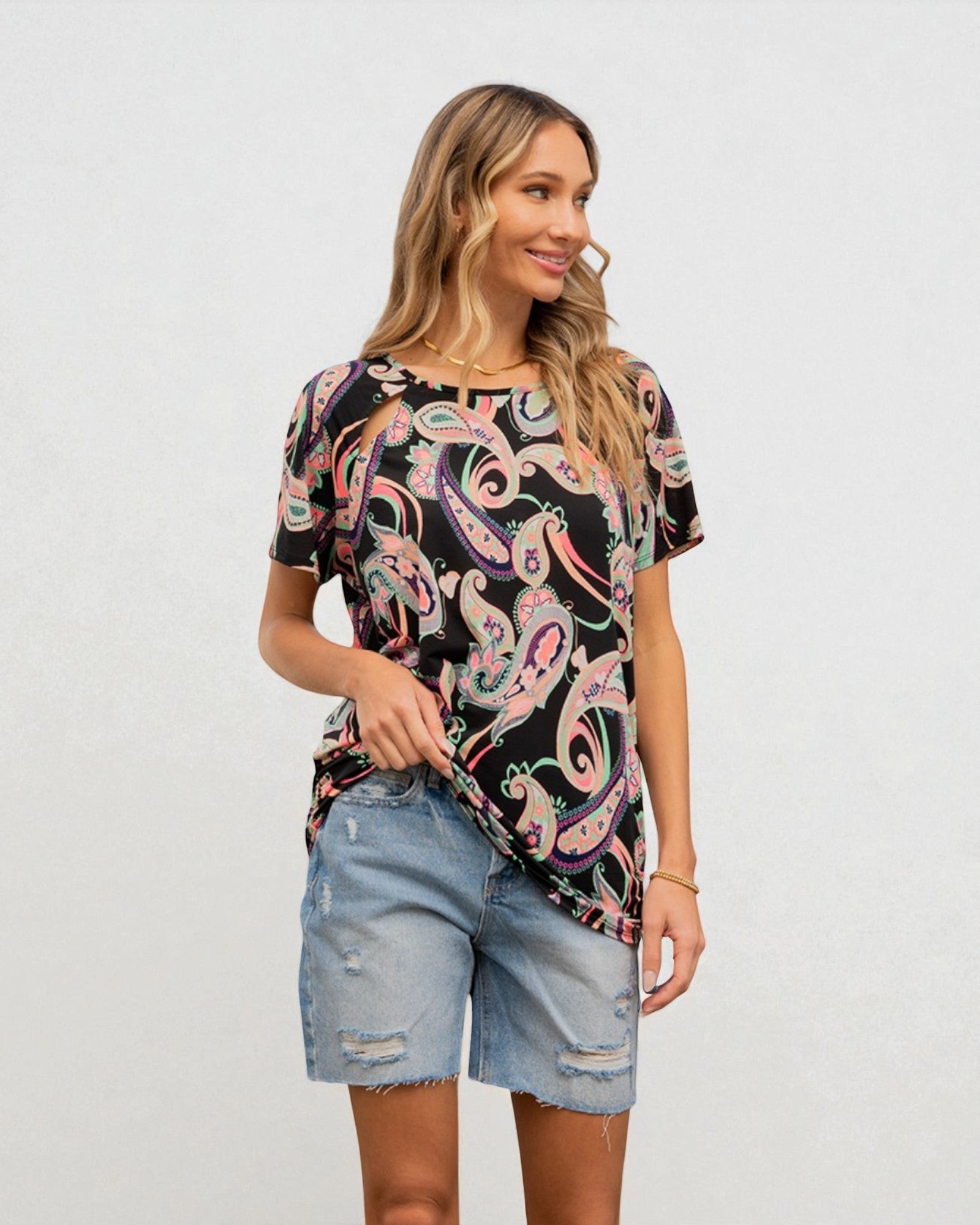 Woman wearing a colorful paisley shirt and denim shorts on a white background