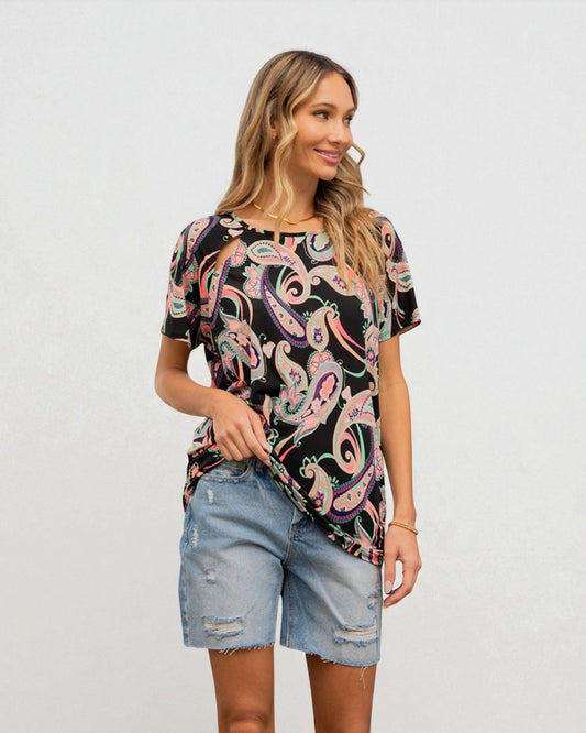 Woman wearing a colorful paisley shirt and denim shorts on a white background