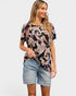 Woman wearing a black t-shirt with colorful paisley pattern and denim shorts on a white background