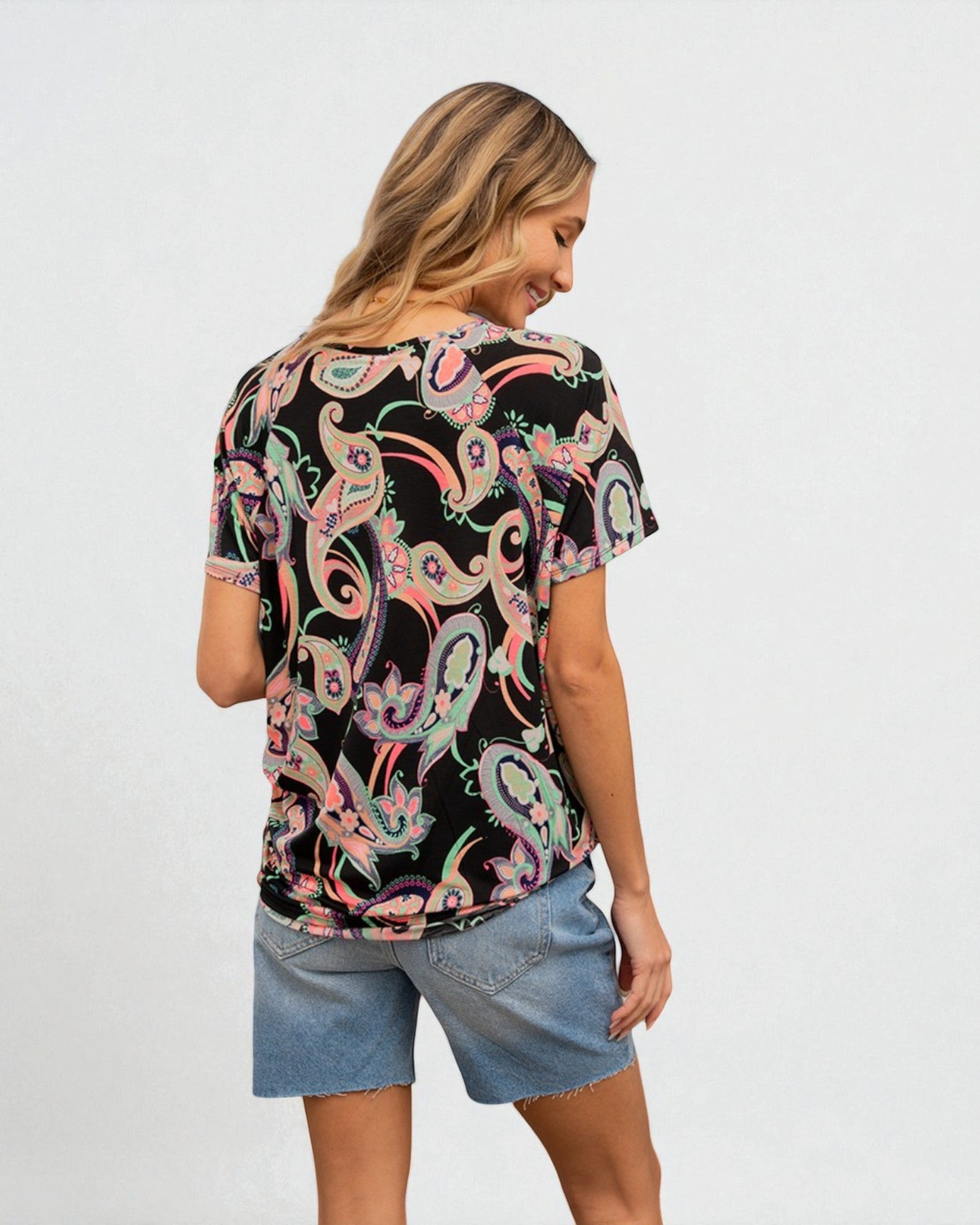 Woman wearing a black patterned top and denim shorts on a white background