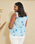 Woman wearing a light blue floral sleeveless top against a beige background
