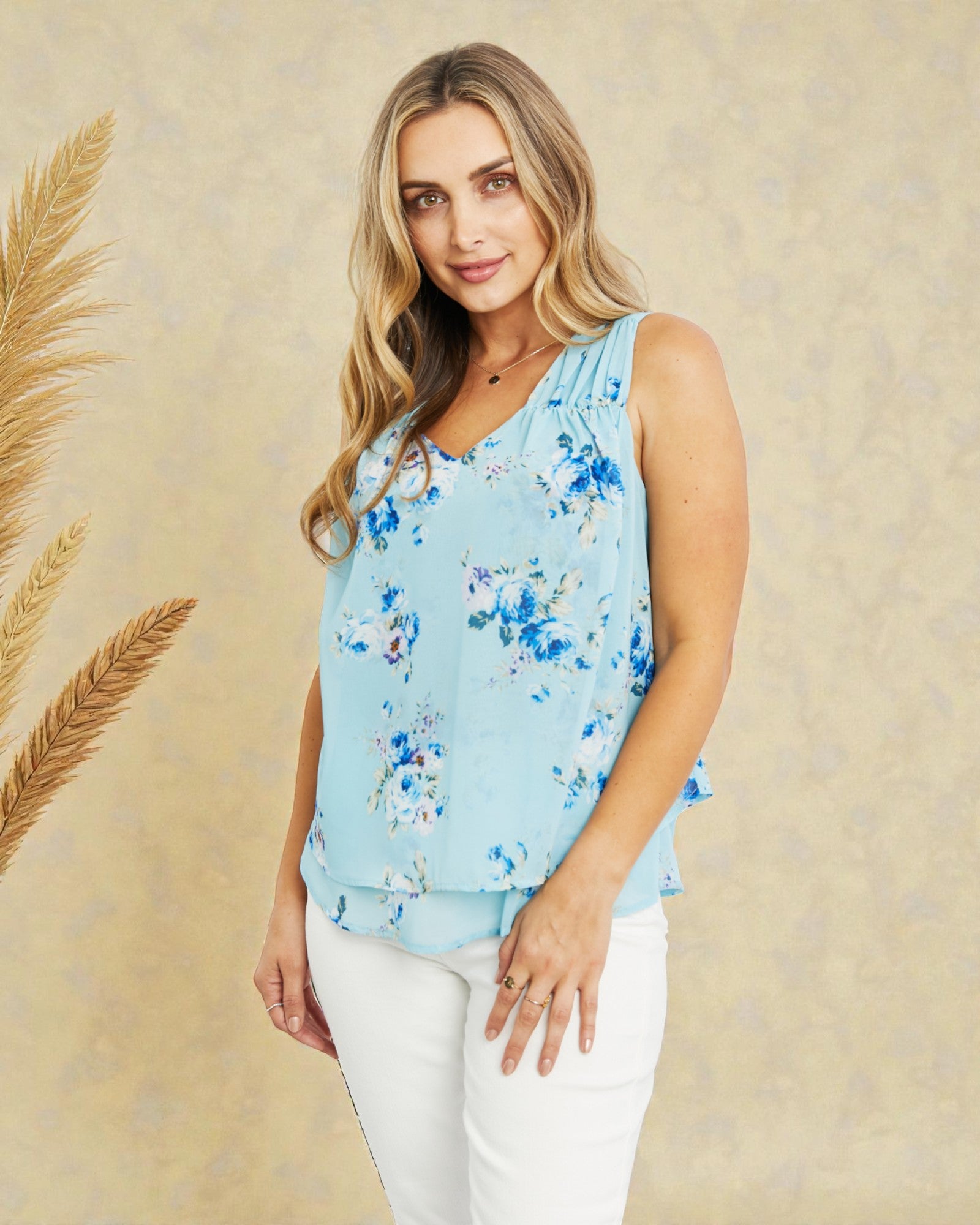Woman wearing a light blue floral sleeveless top against a beige background