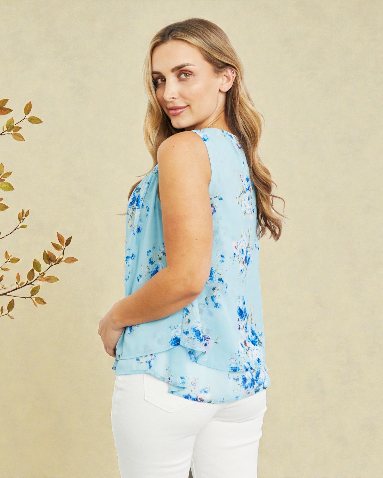 Woman wearing a light blue floral sleeveless top against a beige background