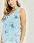 Woman wearing a light blue floral sleeveless top against a neutral background