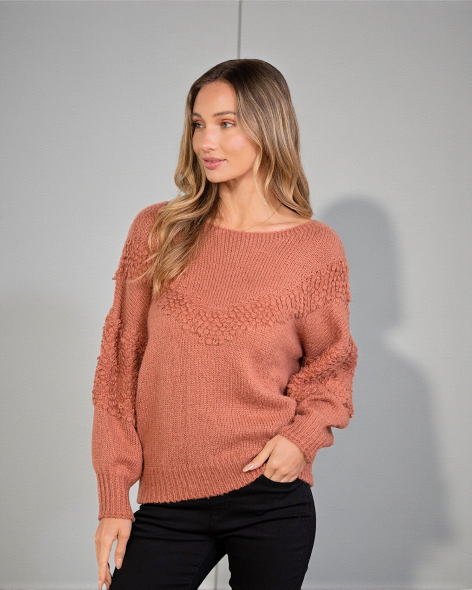 Woman wearing a brown sweater against a gray background