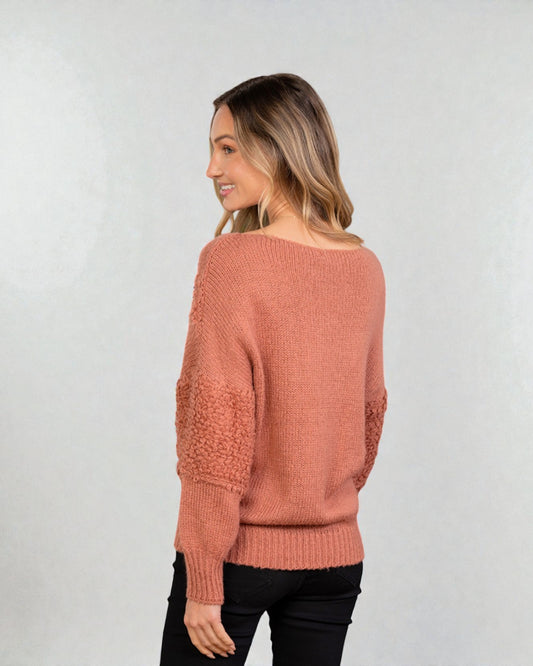 Woman wearing a pink sweater against a plain background
