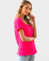 Woman wearing a bright pink textured top against a white background