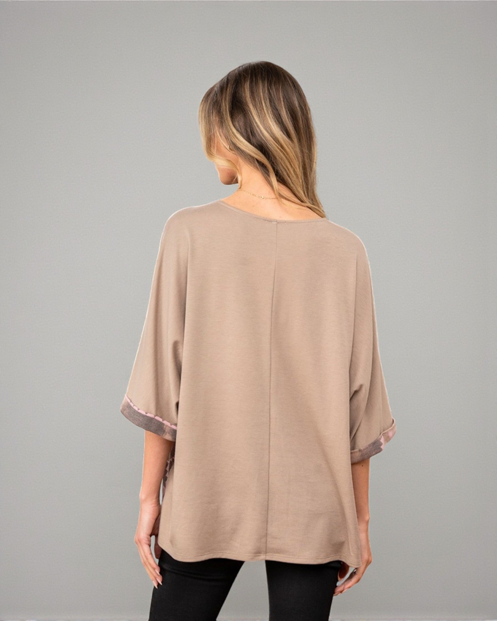 Woman wearing a beige blouse against a gray background