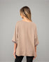 Woman wearing a beige blouse against a gray background