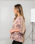 Woman wearing a patterned top in a studio setting with lighting equipment.