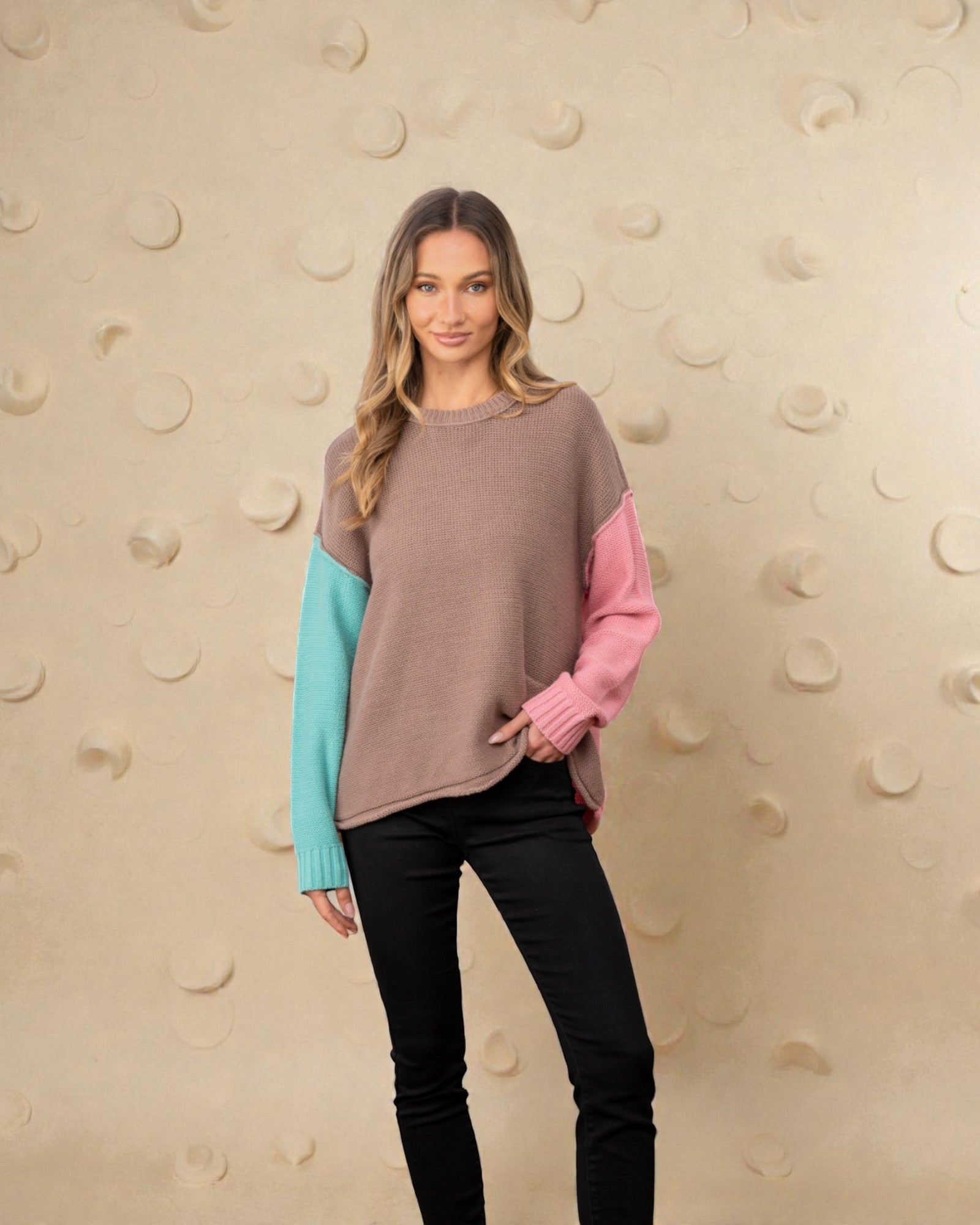 Woman wearing a multicolored sweater with a beige wall background