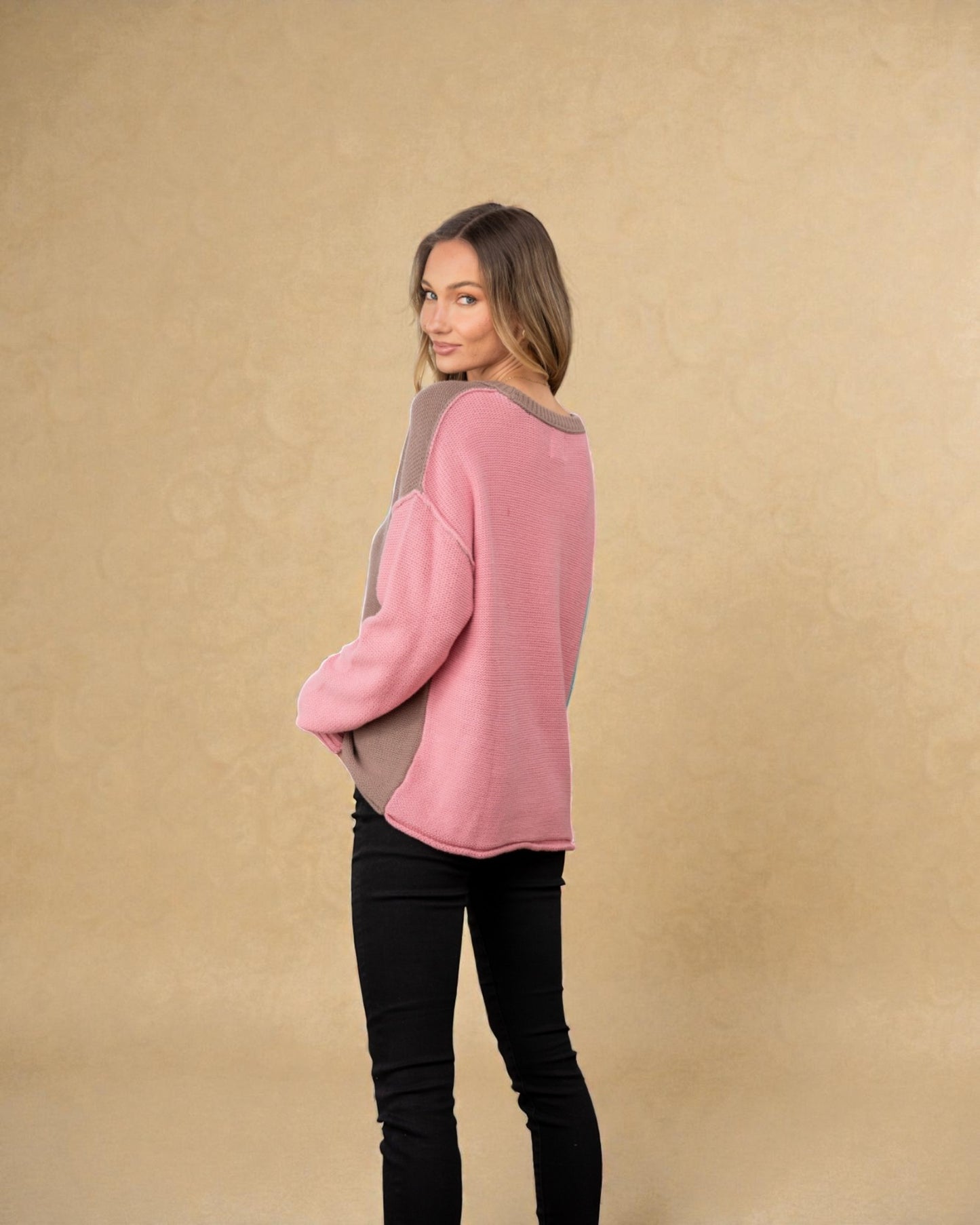 Woman wearing a pink sweater with gray accents against a beige background