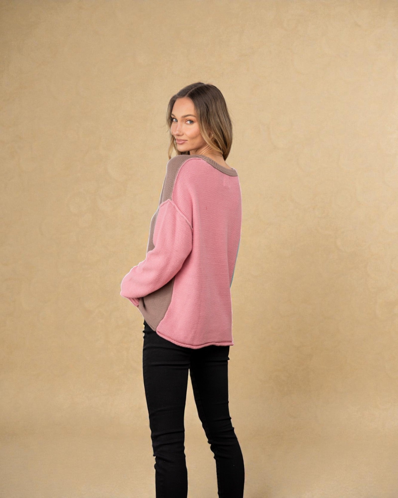 Woman wearing a pink sweater with gray accents against a beige background