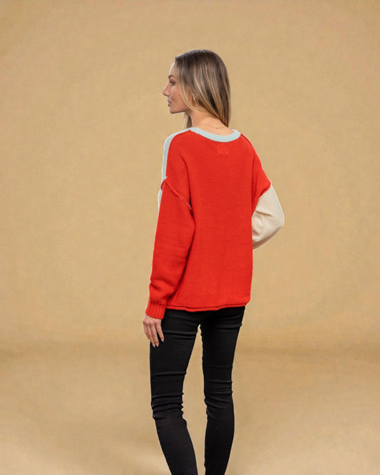 Woman wearing a red sweater with a beige shirt underneath on a beige background