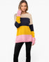 A woman modeling a color-blocked knit sweater with horizontal stripes of beige, navy, yellow, and pink, paired with black pants against a plain white background.