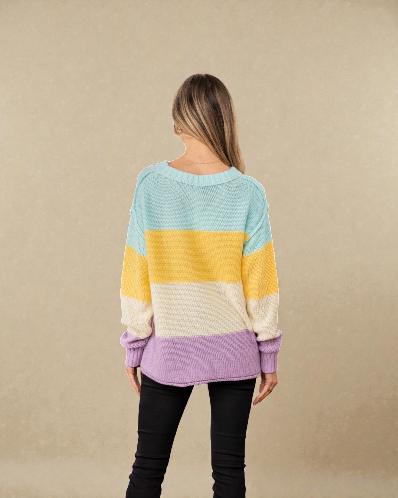 Woman wearing a colorful striped sweater against a beige background