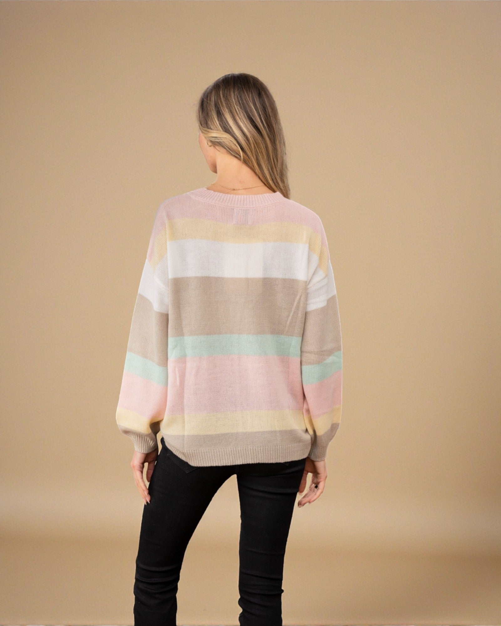 Person wearing a pastel striped sweater on a beige background