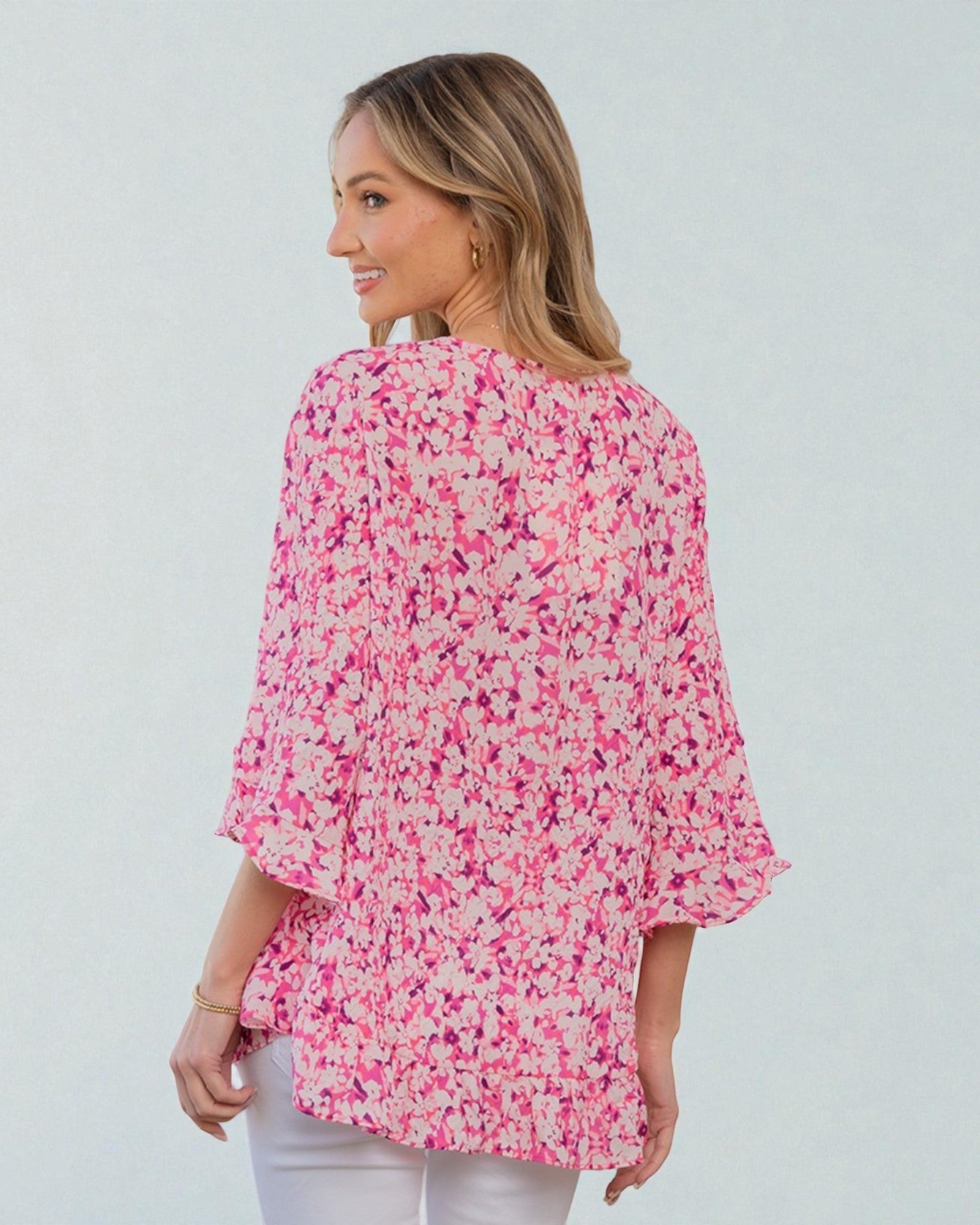 Woman wearing a pink floral blouse against a white background