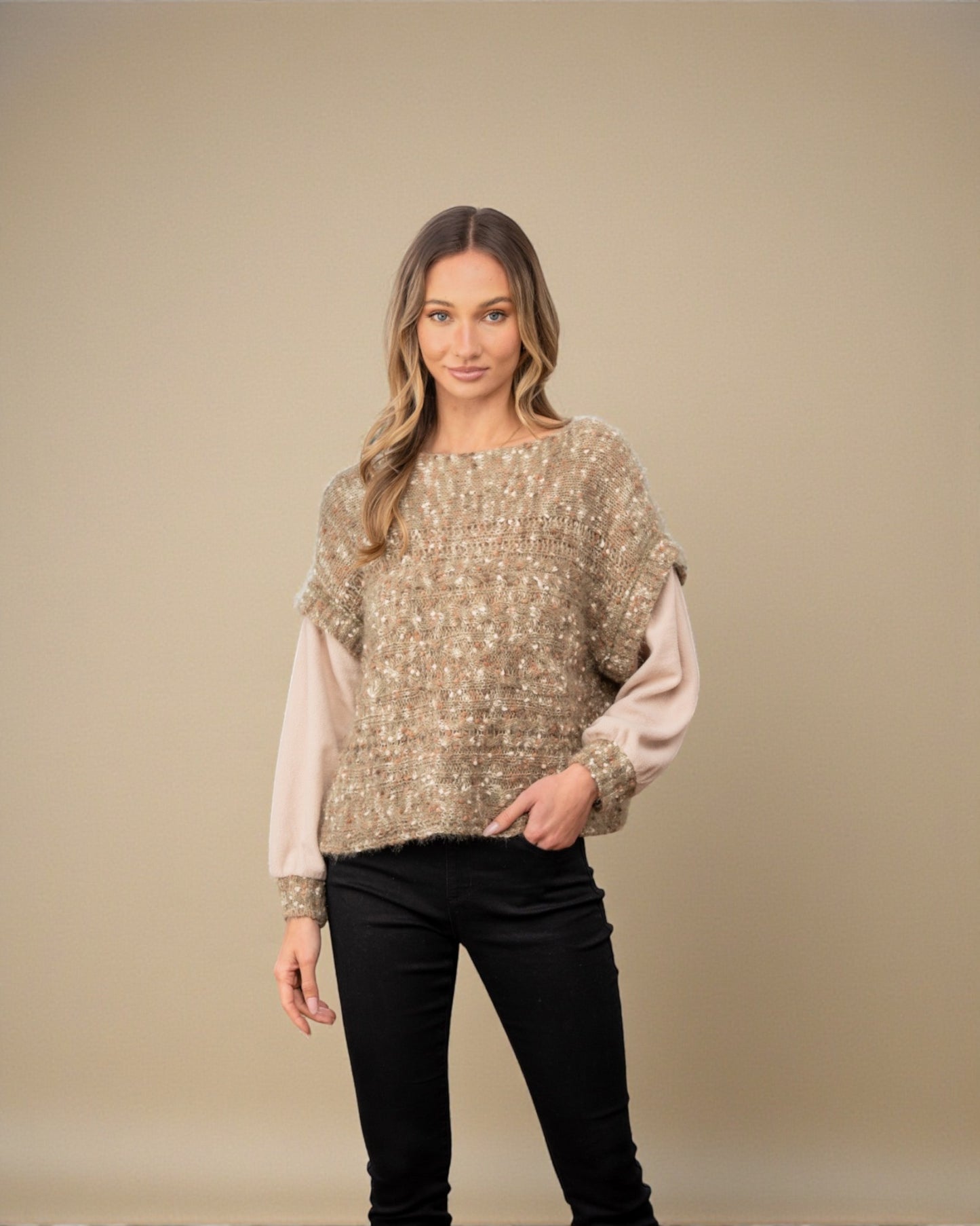 Woman wearing a gold sequin top over a pink shirt with black pants on a beige background