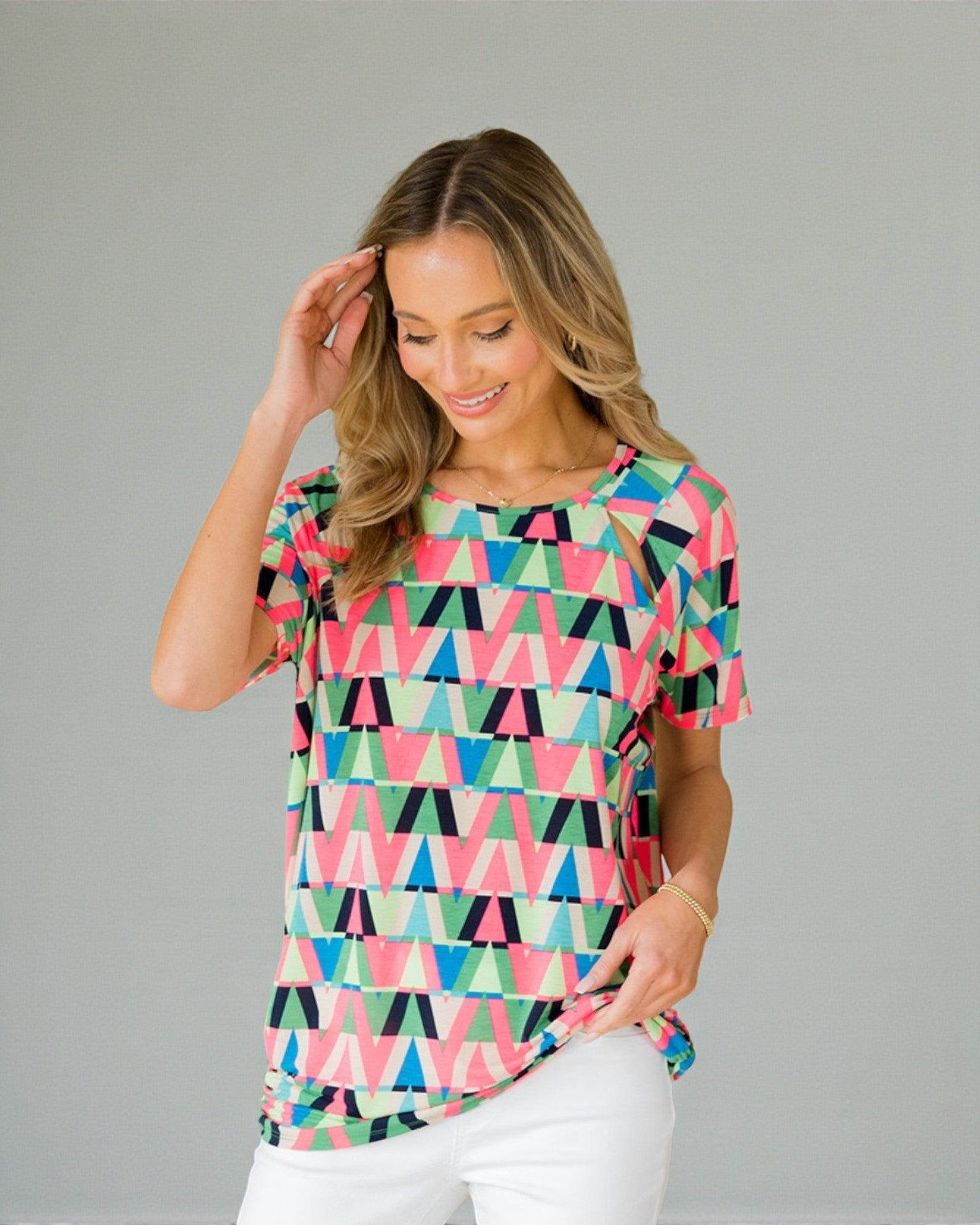 Woman wearing a colorful geometric patterned top against a gray background