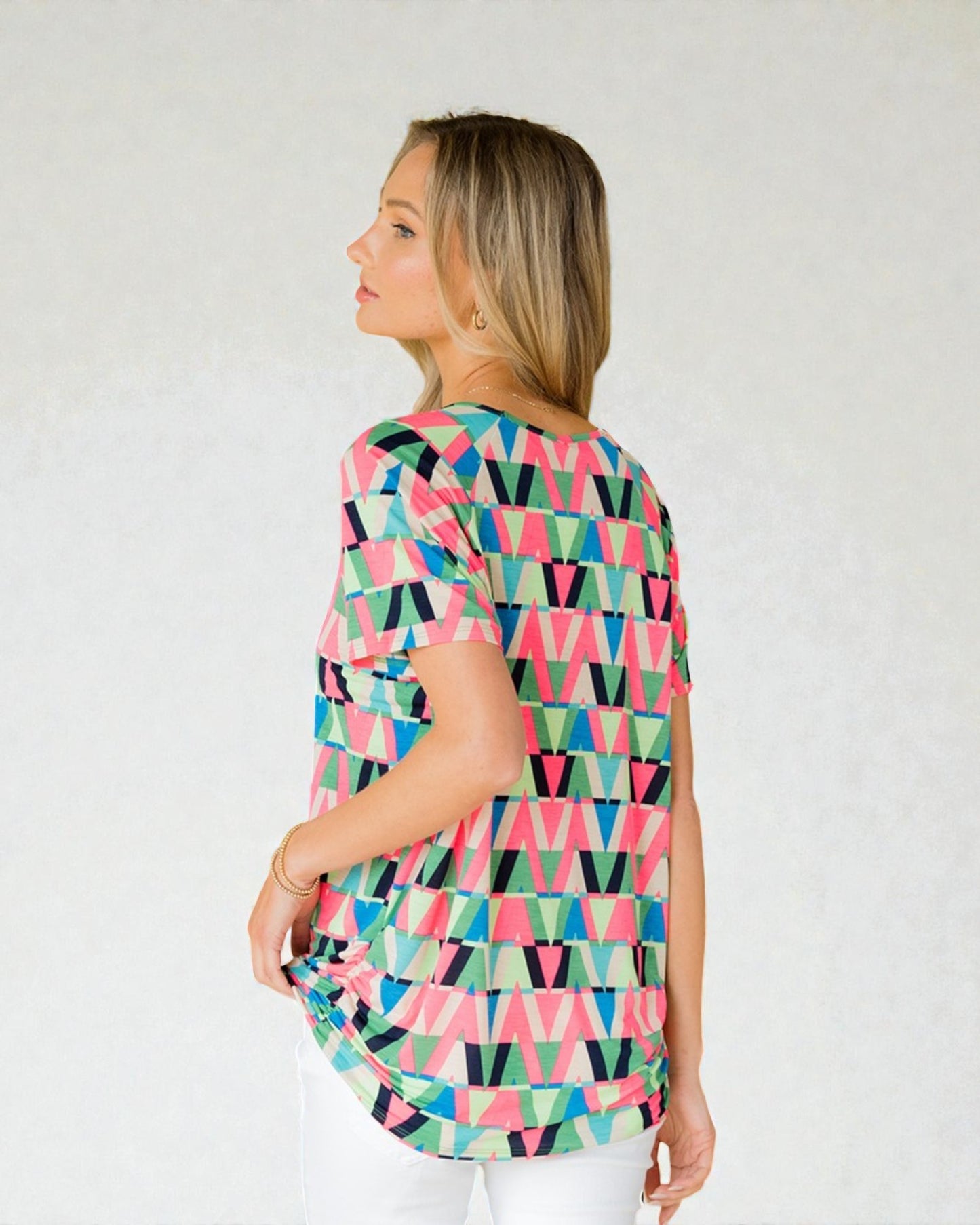 Woman wearing a colorful geometric patterned top against a white background