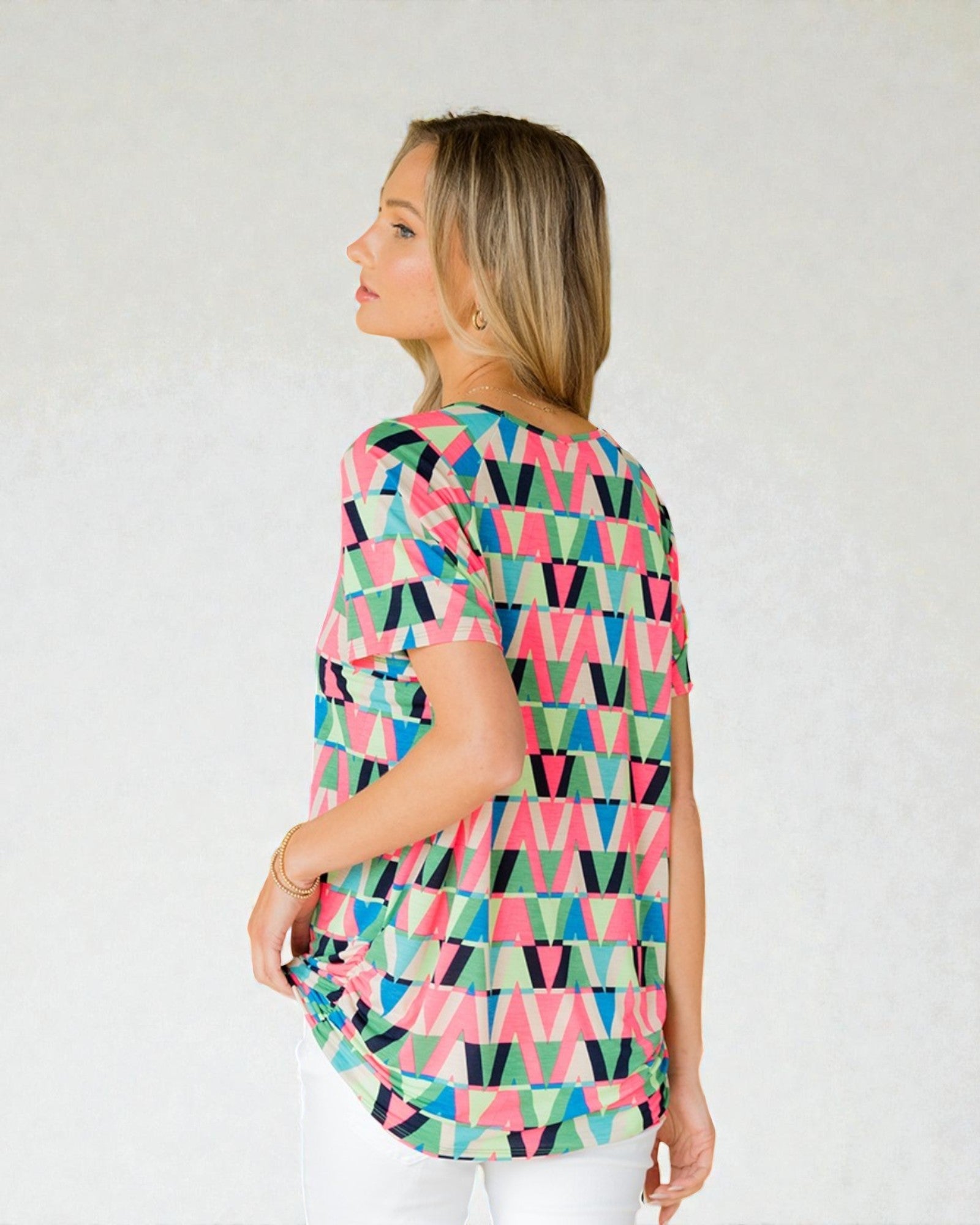 Woman wearing a colorful geometric patterned top against a white background