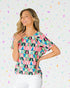 Woman wearing a colorful geometric patterned top against a multicolored confetti background