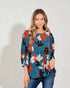 Woman wearing a colorful floral blouse against a plain background