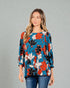 Woman wearing a colorful floral blouse against a gray background