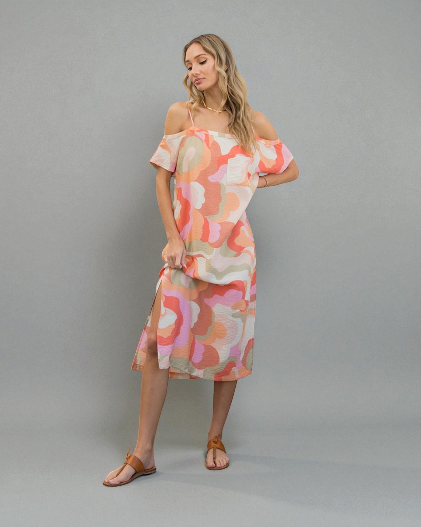 Woman wearing a colorful off-shoulder dress against a gray background