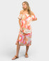 Woman wearing a colorful off-shoulder dress on a white background