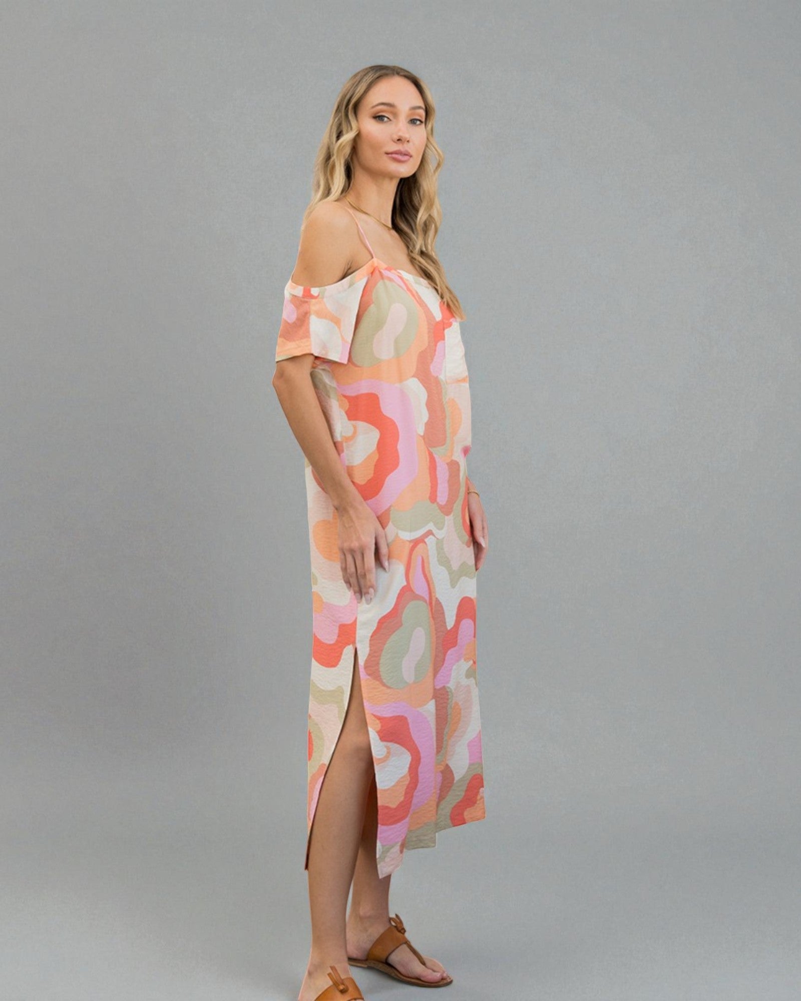 Woman wearing a colorful off-shoulder dress on a gray background