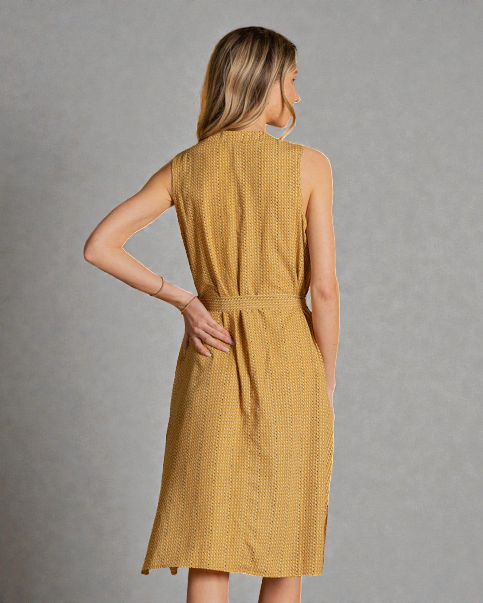 Woman wearing a mustard yellow dress against a gray background