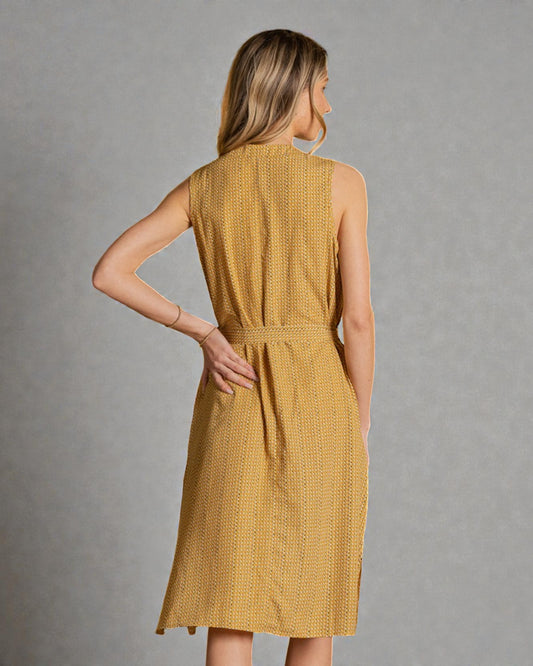 Woman wearing a mustard yellow dress against a gray background