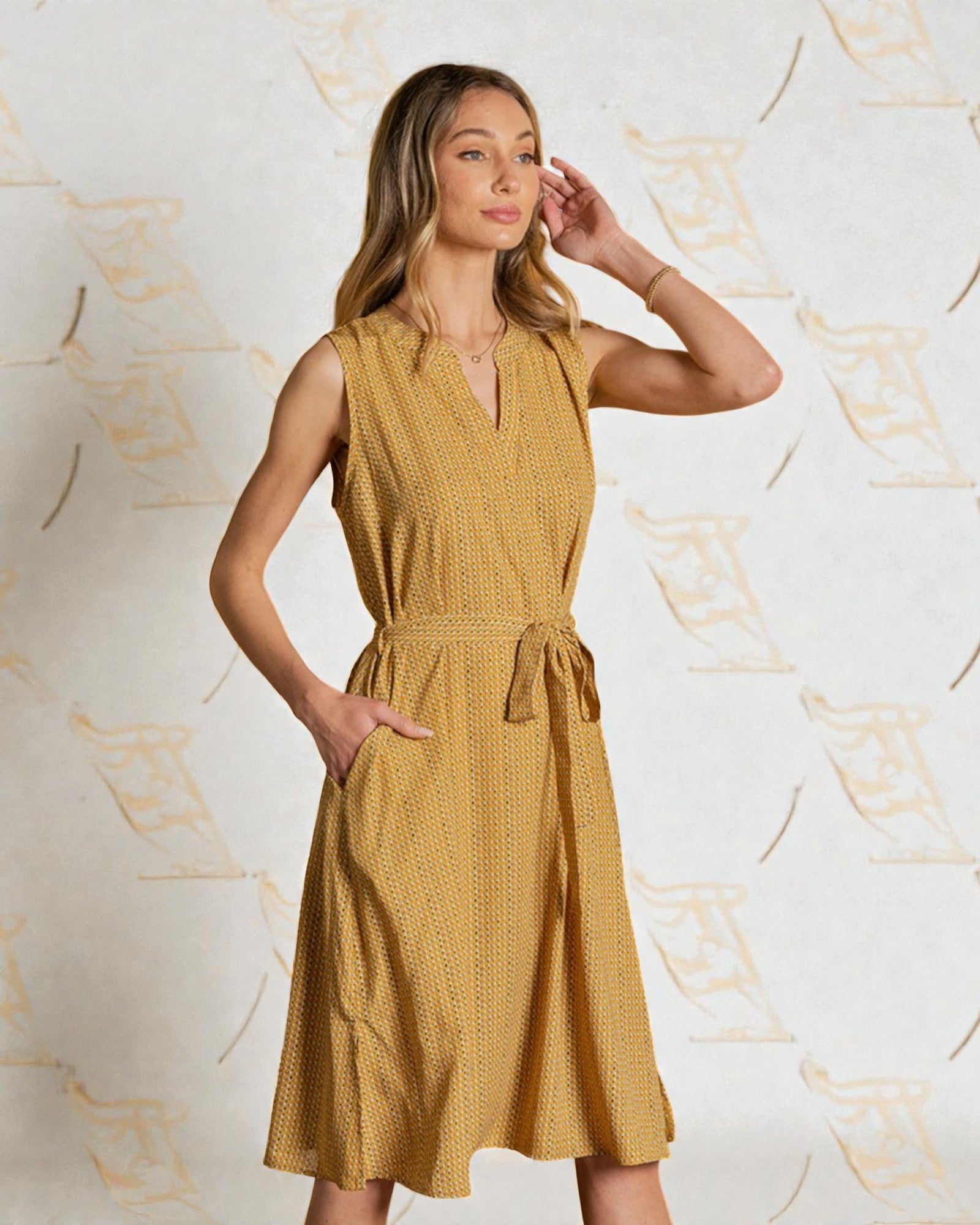 Woman wearing a mustard yellow dress against a decorative background