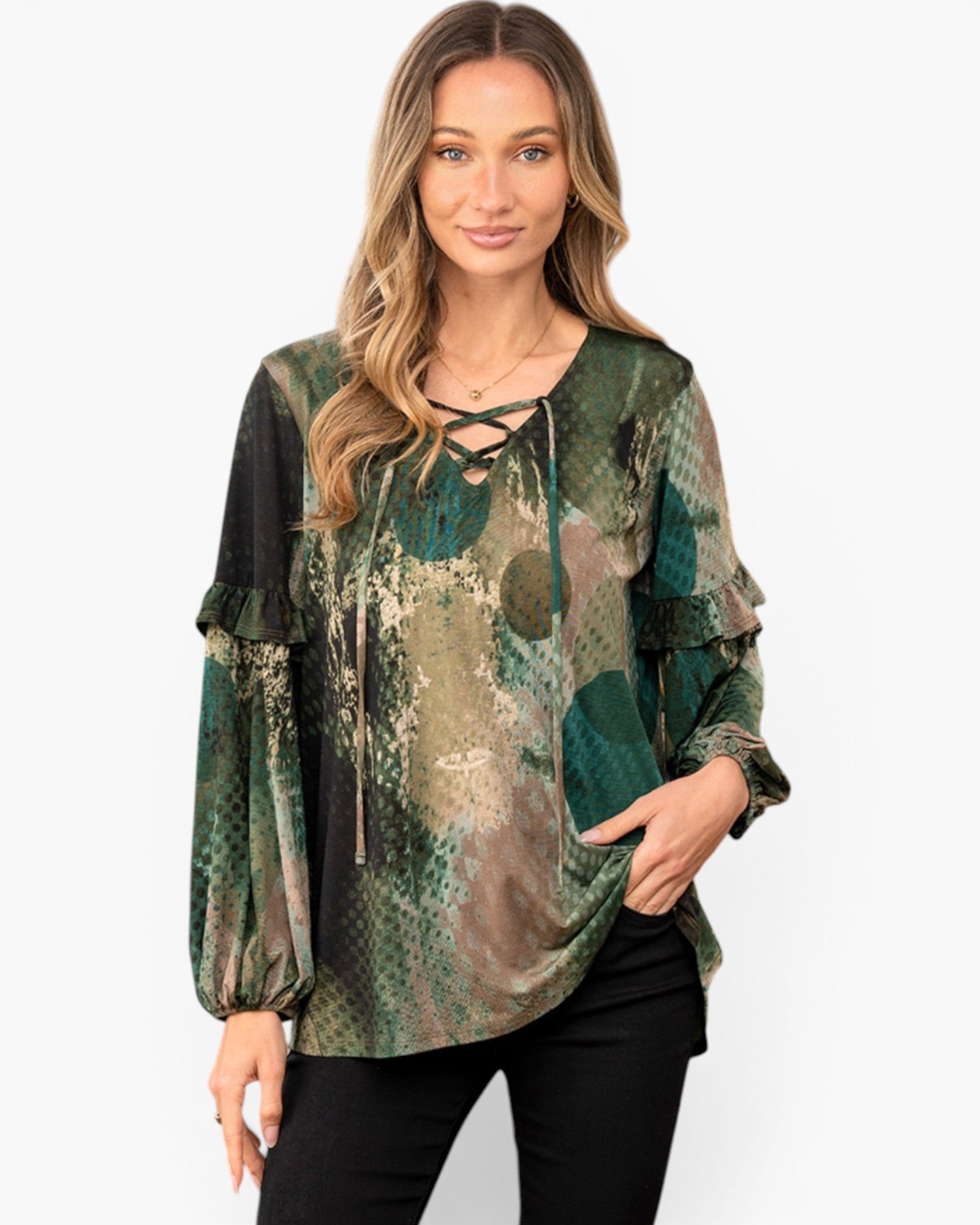 A woman modeling a long-sleeve blouse with a green, brown, and beige snakeskin print, featuring a lace-up neckline and ruffled cuffs, paired with black pants against a light gray background.